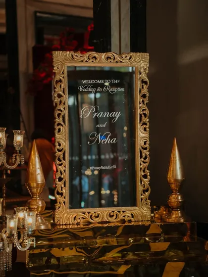 A close-up of the ornate, gilded mirror used as a welcome sign for a wedding reception. Even the smallest details are chosen to reflect the event's regal theme.