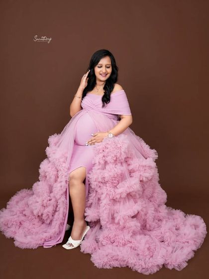 A beautiful portrait of a mother-to-be seated in a lavender gown. The flowing ruffles and her serene expression create a dreamy and elegant image.