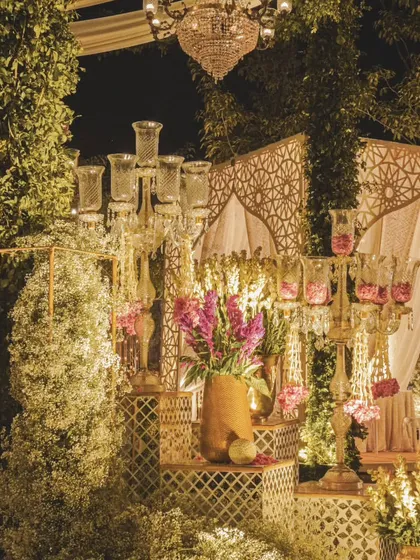 A grand floral and lighting installation for a wedding ceremony. We layered baby's breath, pink blooms, and elegant candelabras against a traditional jaali backdrop to create this magnificent display.