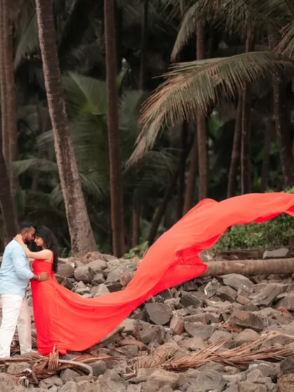 A romantic walk on the beach. The vibrant red trail gown flows behind the couple, creating a beautiful and memorable pre-wedding image.