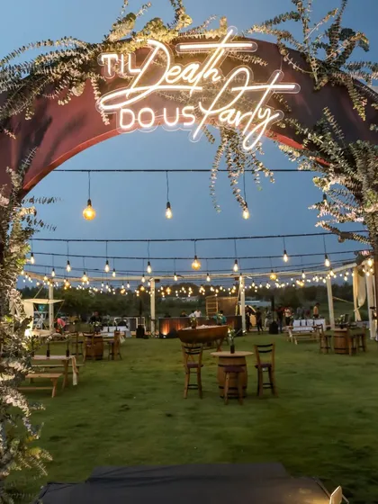 Let the party begin. We designed this rustic-chic Mehendi entrance with a playful neon sign, "Til Death Do Us Party," setting a fun and modern tone for the celebration. It’s the perfect welcome for an evening of joy and dancing.