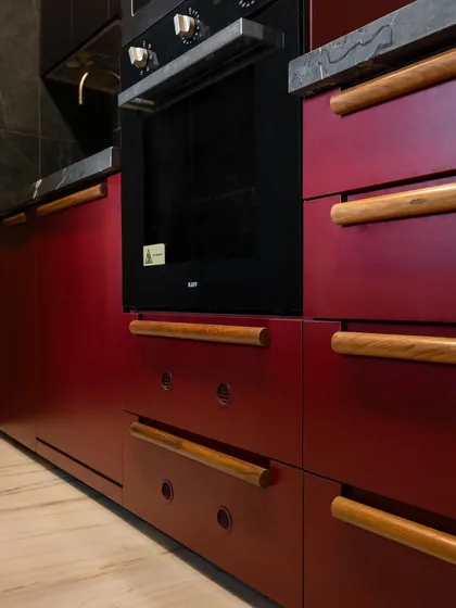 Colour can be a powerful way to express personality. This kitchen, with its deep Marsala red cabinetry and custom wooden handles, shows how a bold choice, when balanced with natural textures and clean lines, can create a space that feels both confident and incredibly warm.