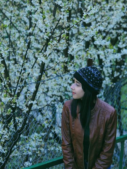 A young woman stands beside a blossoming tree in Himachal, the white flowers creating a beautiful, soft backdrop. This portrait captures the feeling of finding beauty in nature and accepting oneself, a theme I often explore on my travels.