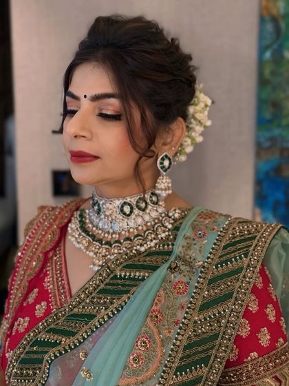 A bride with her eyes gently closed, showcasing the flawless bridal makeup. We focused on a soft glam eye with a classic red lip, complemented by a voluminous updo adorned with fresh gajra for a traditional yet polished look.