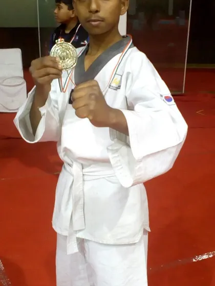 A young champion in his fighting stance, holding his gold medal. This is the look of a proud and accomplished martial artist.