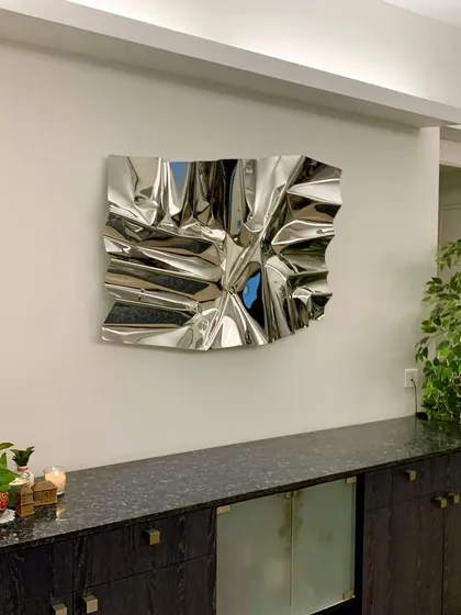 A classic silver Meteor sculpture installed in a client's home, adding a touch of modern sophistication above a dark wood console.