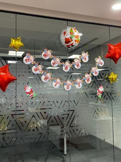 Another example of a Christmas banner and foil balloon decoration on an office's glass partition.