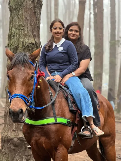 Two friends enjoying a horse ride through the pine forest.