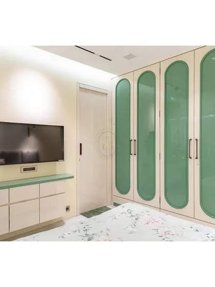 This image highlights the custom wardrobe I designed with glossy, rounded green panels. The high-gloss acrylic finish reflects light beautifully, making the room feel brighter, while the unique shape adds a playful yet sophisticated element to the bedroom's overall design.