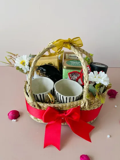 This angle highlights the lush red ribbon and the arrangement of flowers and gifts in the Kauna oval basket hamper.