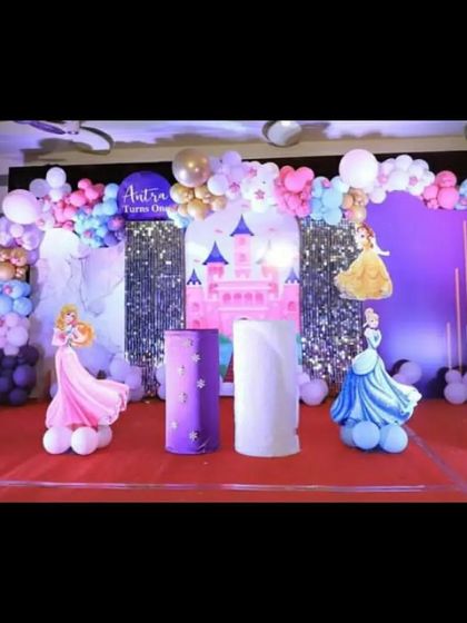 A grand princess castle stage setup for a first birthday. Featuring cutouts of Snow White, Sleeping Beauty, and Cinderella on balloon clouds, this makes for a magical photo opportunity.