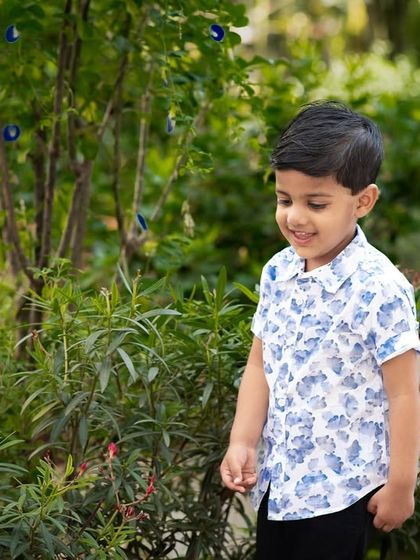 A candid shot of a boy exploring a garden. The natural setting and his curious expression create a lovely, authentic childhood portrait.