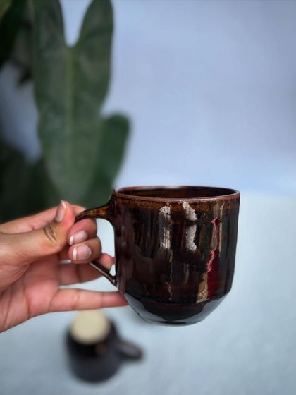Holding a Tenmoku mug. The way the light reflects off the glossy surface is just beautiful.