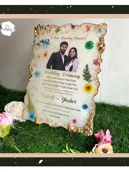 A full view of the resin wedding invitation, displayed on a stand and surrounded by flowers.