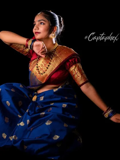 A dynamic portrait capturing a traditional dance-like pose. This image showcases the flow and elegance of the saree and the cultural richness of the attire in a single, powerful frame.