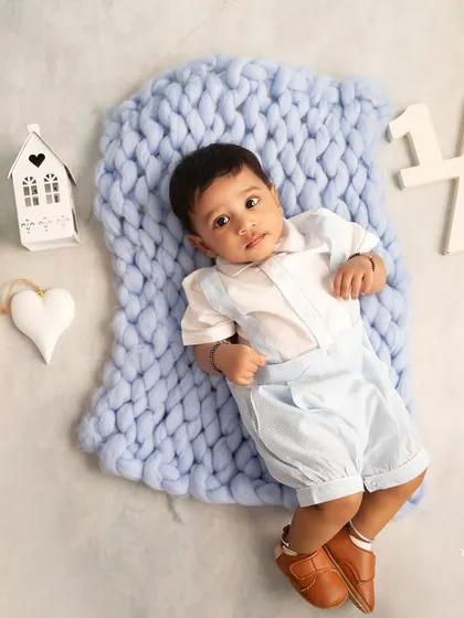 Six months of sweetness. This sitter session portrait shows the baby lying on a chunky knit blanket, a perfect way to capture the half-year milestone.