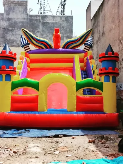 Another view of the castle bouncy with winged tower details, showcasing its bright, primary color scheme.