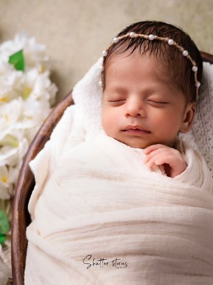 A tighter shot of the all-white setup, emphasizing the baby's delicate features and the texture of the wrap.