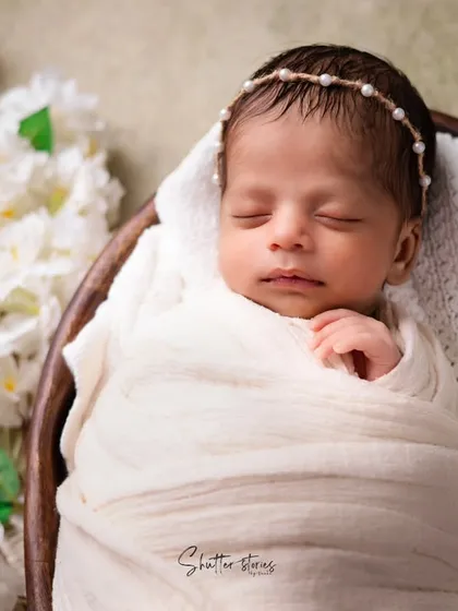 A tighter shot of the all-white setup, emphasizing the baby's delicate features and the texture of the wrap.