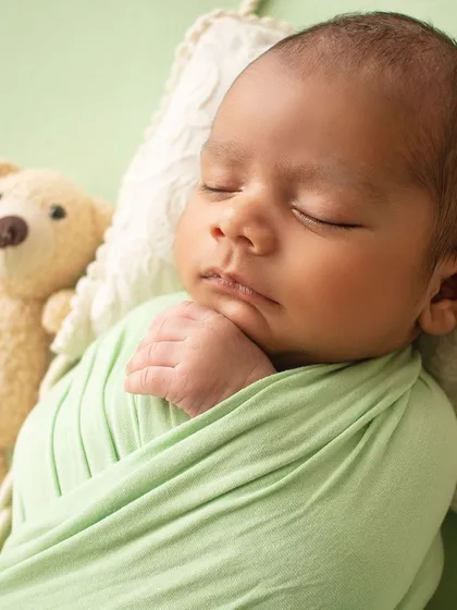 A close-up portrait of a sleeping newborn, showing the delicate features of his face.