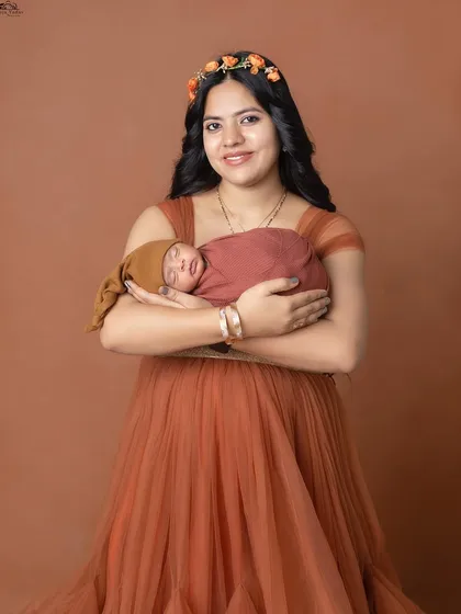 A beautiful portrait of a mother holding her newborn. The floral headband adds a lovely, soft touch.