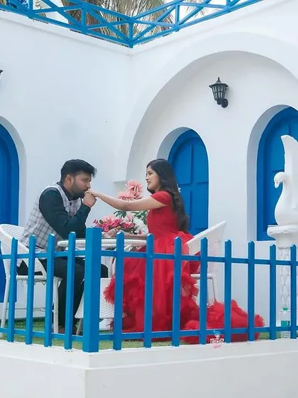 A chivalrous moment as the groom-to-be kisses his partner's hand on the balcony of the Santorini set. A truly romantic pre-wedding photo.