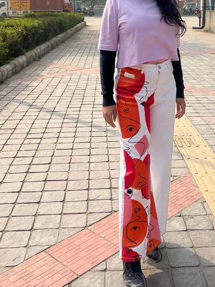 A close-up of the hand-painted abstract faces on these white denim pants. I love working with unique, artistic pieces to create a look that is truly one of a kind.