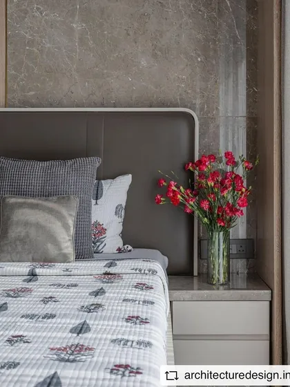 A serene bedroom setting with a grey marble accent wall, showcasing how a pop of color from fresh flowers can liven up a neutral space.