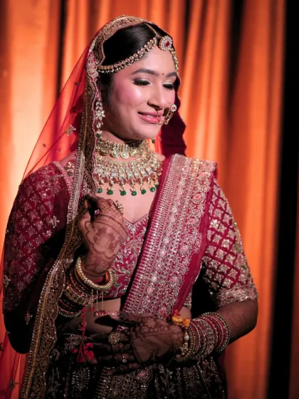 This bride's gentle smile is the highlight of this photo. The makeup is soft and elegant, perfectly complementing her traditional red and gold ensemble.