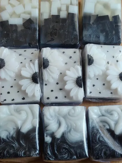 A collection of black and white themed soaps, showing different artistic techniques from swirls to floral appliques.