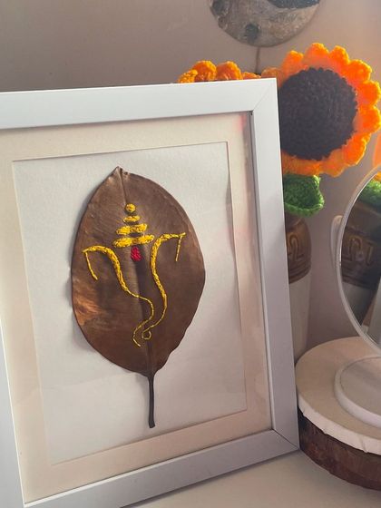 My framed Ganpati leaf embroidery sitting on my desk. It's a peaceful reminder of faith and art combined, and it makes a unique piece of spiritual home decor.