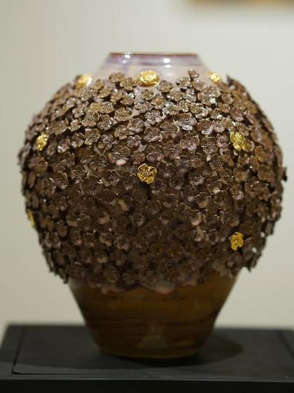 The finished 'Floral Grace' vase, displayed as a piece of art. The combination of the earthy clay texture and the delicate, shimmering gold accents creates a beautiful contrast.