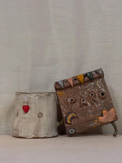 A student's love story in clay. This set, featuring a heart-stamped mug and a storybook-inspired wall hanging, shows the beautiful narrative that can be created in a single workshop session.