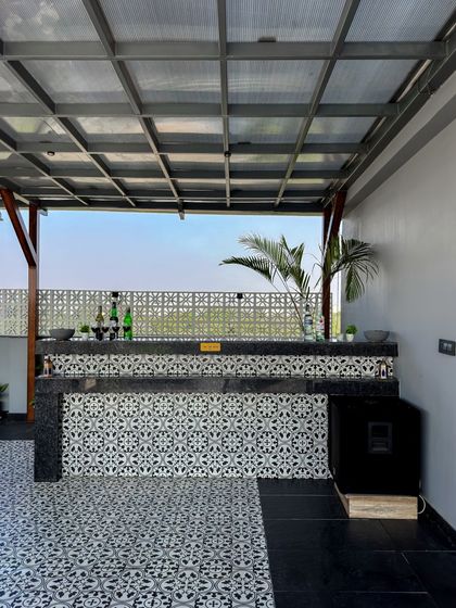 This bar combines modern and classic elements, with a patterned tile front and a sleek black countertop. It's a functional and stylish addition to this covered terrace lounge.