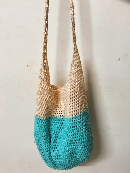 A full view of the mesh tote bag hanging. The open stitch work makes it a great, breathable bag for produce or beach towels.