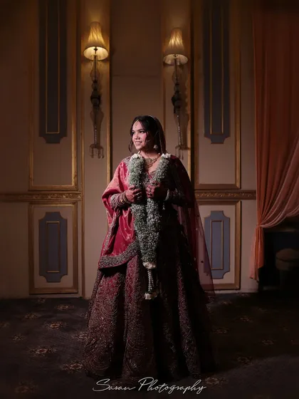 A full-length bridal portrait in a dimly lit, classic room, creating a moody and sophisticated atmosphere.