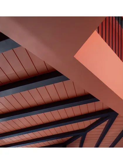 An abstract view of the ceiling and structural beams within the Baia Villas veranda. The contrast between the dark beams and the warm, textured ceiling highlights the careful consideration of materials and their interplay.
