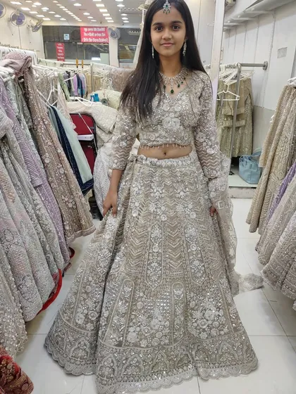 A full-length photo of the young client in the silver-grey lehenga.