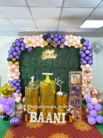 A unique butterfly theme using a grass wall backdrop. The purple and peach balloons look beautiful against the green, and the golden shimmer pedestals add a touch of luxury.