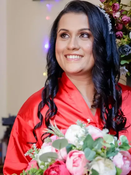 The bride, glowing with anticipation, holds her bouquet. Her hair is styled in soft curls, and she's ready for her wedding day to begin.