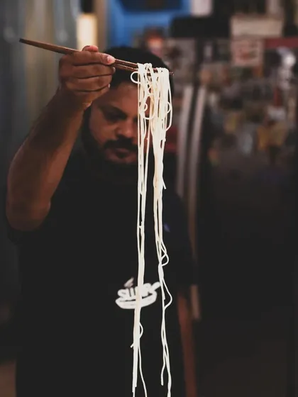 Holding up freshly made noodles, a testament to the hands-on skills learned during our immersive Chinese Cuisine Masterclass.