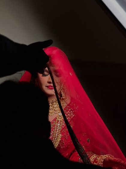 A behind the scenes shot of the photographer adjusting the veil. It shows the collaborative effort to get the perfect bridal portrait.