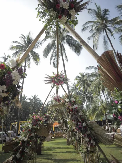 A unique triangular entrance arch designed for a tropical-themed carnival. The structure, made of bamboo and adorned with dried palms and fresh flowers, created a striking and natural gateway to the event.