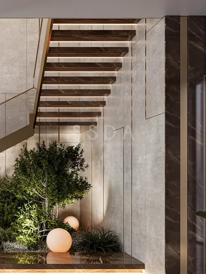A close-up of the indoor garden beneath the staircase. The combination of natural plants, soft lighting, and rich materials like wood and marble creates a serene and layered experience.