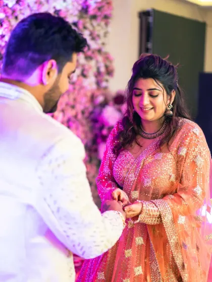 The bride places the ring on the groom's finger, a moment of mutual commitment and love, captured in a candid style.