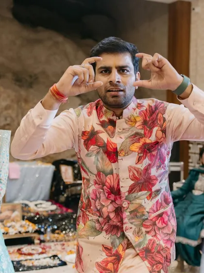 The groom having some fun at his mehendi. A closer look at the vibrant floral print on his jacket, a key piece that defines his fun and festive look for the event.