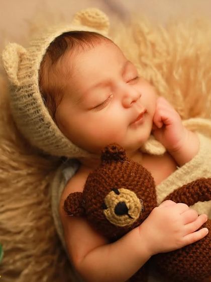 A sweet portrait of baby Miraya wearing a knitted bear bonnet and holding a matching teddy bear. These simple props add a touch of whimsy without distracting from the baby's natural beauty.