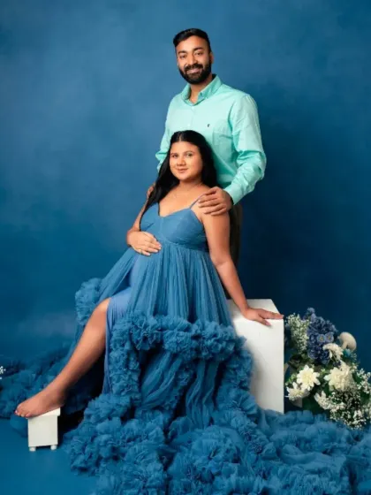 Create a beautiful memory with your partner. This flowing blue tulle gown with a ruffled train offers a romantic and ethereal look, perfect for capturing the connection and joy of your pregnancy journey together.