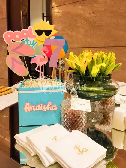 The details make the party. A custom centerpiece for a pool party, featuring fun cutouts like a sun with sunglasses, flip-flops, and a flamingo.