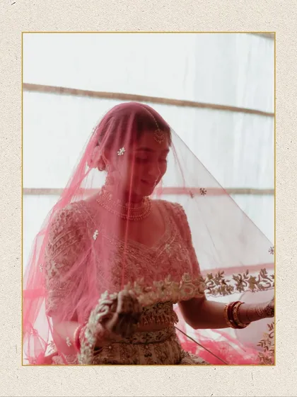 An artistic shot of the bride through her sheer pink veil. The soft focus and warm light create a dreamy and ethereal bridal portrait.